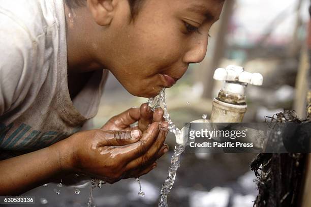 Child is drinking water while his parents work on a coal field. Laborers leave home for a better income, they get only $7.5 for 12 hours work.