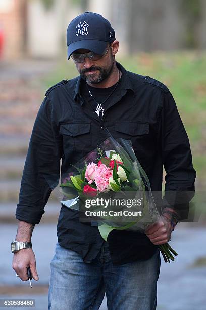Man carries flowers to lay outside the Oxfordshire home of British pop singer George Michael on December 26, 2016 in Goring, England. Singer George...