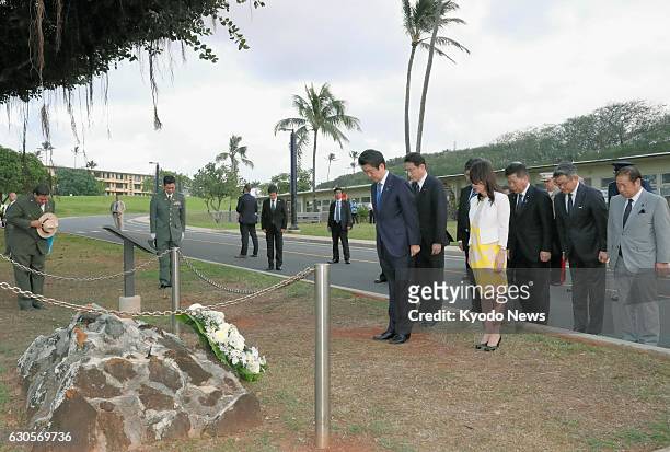 Japanese Prime Minister Shinzo Abe observes a moment of silence after placing a wreath at a memorial to Lt. Fusata Iida, a Japanese naval pilot who...