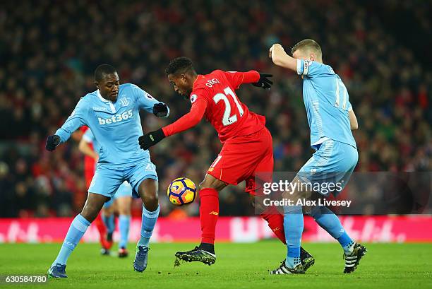 Divock Origi of Liverpool battles with Gianelli Imbula and Ryan Shawcross of Stoke City during the Premier League match between Liverpool and Stoke...