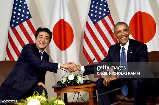 President Barack Obama shakes hands with Japanese Prime Minister Shinzo Abe December 27, 2016 during a meeting in Honolulu, Hawaii prior to visiting...