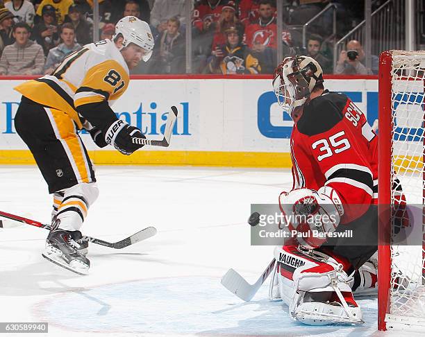 Goalie Cory Schneider of the New Jersey Devils stops a shot by Phil Kessel of the Pittsburgh Penguins in the first period of an NHL hockey game at...