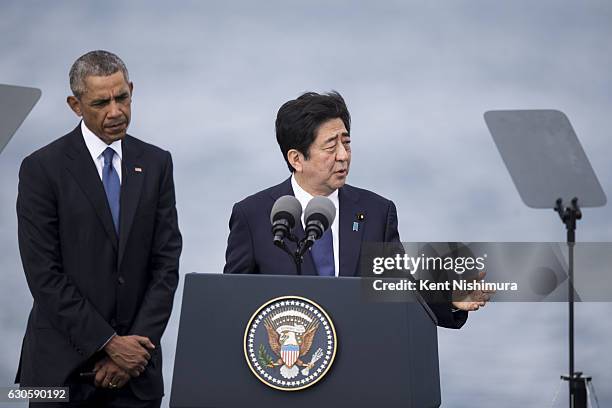 President Barack Obama listens while Japanese Prime Minister Shinzo Abe delivers remarks at Joint Base Pearl Harbor Hickam's Kilo Pier on December...