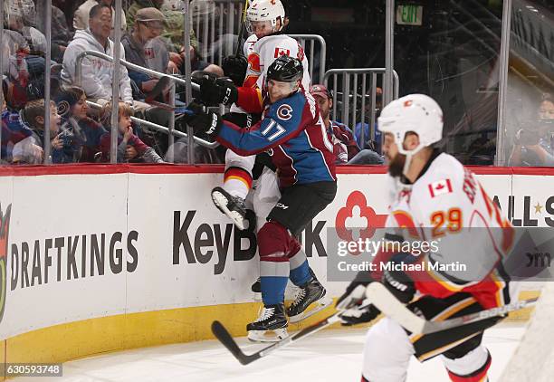 Rene Bourque of the Colorado Avalanche checks Jyrki Jokipakka of the Calgary Flames into the glass at the Pepsi Center on December 27, 2016 in...