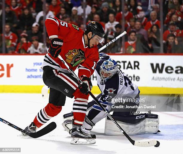 Artem Anisimov of the Chicago Blackhawks gets past Connor Hellebuyck of the Winnipeg Jets to score a second period goal at the United Center on...
