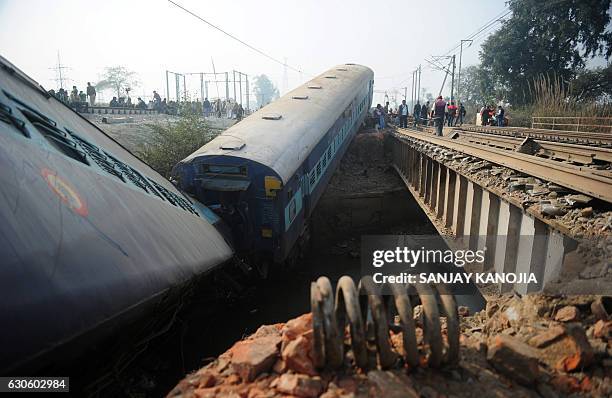 Indian officials and bystanders gather alongside derailed train carriages at Rura, some 30 kms west of Kanpur on December 28 following a train crash...