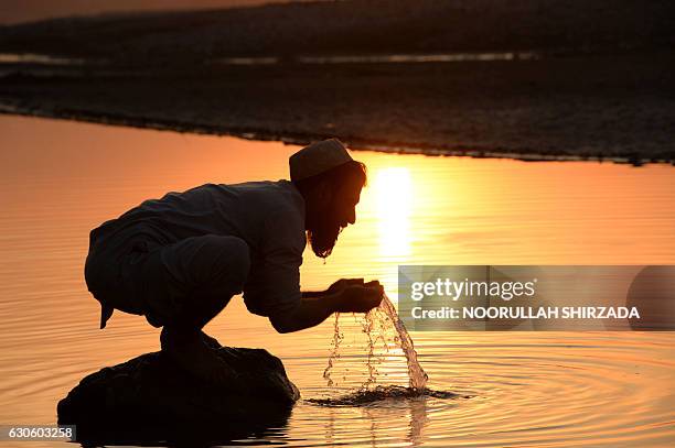 In this photograph taken on December 27 an Afghan man performs ablution before prayers in a river on the outskirts of Jalalabad. / AFP / NOORULLAH...