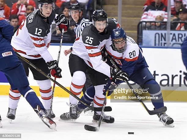 Slovakia forward Adam Ruzicka battles for the puck with Canada forwards Nicolas Roy and Julien Gauthier in the first period at the World Junior...