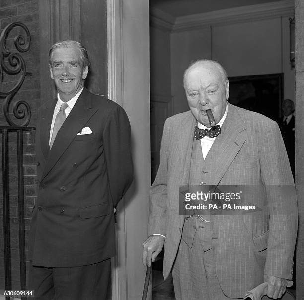 Prime Minister Sir Anthony Eden smiles as he comes to the door of No 10 Downing Street, London, with Sir Winston Churchill, his predecessor in...