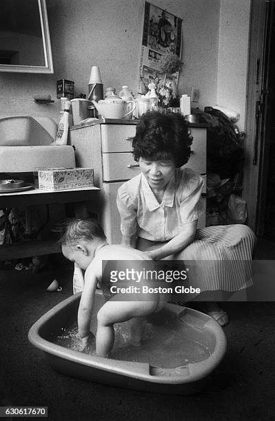 Yu Xiao Zhou bathes her son Jason in the living room of the four-room apartment she shares with four other family members, including her mother, Lan...