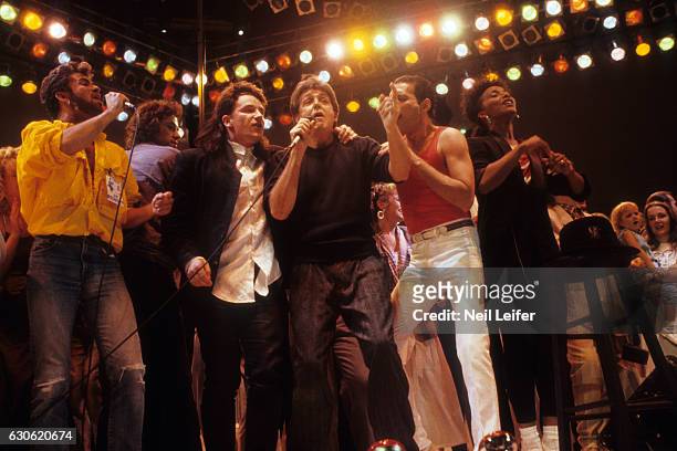 George Michael of Wham with Bono of U2, Paul McCartney, Freddie Mercury and other artists performing on stage during the finale at Wembley Stadium....