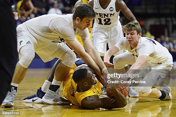 Rodney Williams of the Drexel Dragons tries to pass the ball as Max Rothschild and Ryan Betley, both of the Pennsylvania Quakers, pressure during the...