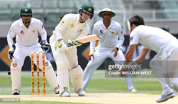 Australia's batsman Nic Maddinson hits the ball back to Pakistan spinner Yasir Shah as wicketkeeper Sarfraz Ahmed and fieldsman Younis Khan look on,...