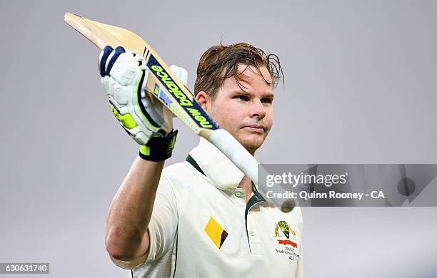 Steve Smith of Australia raises his bat to the crowd as he comes from the field during a rain delay after making his century during day four of the...