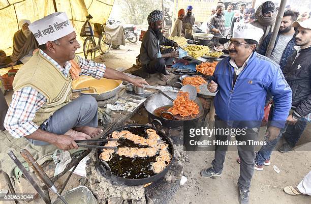 Supporters wearing party caps while purchasing Jalebis from road side vendors near the venue where AAP National Convener and Delhi Chief Minister...