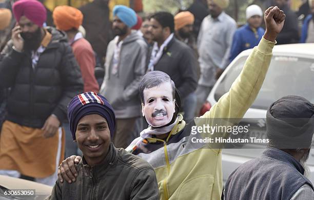 Workers wearing the AAP National Convener and Delhi Chief Minister Arvind Kejriwal's mask in his support, during the roadshow, at village Adda...