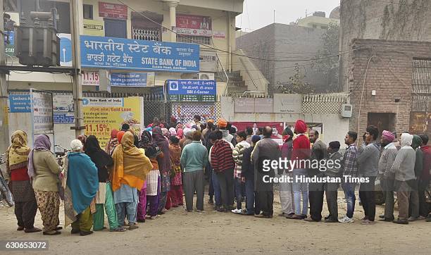Despite cold weather people queuing outside the State Bank of India branch to get cash at Batala Road on December 29, 2016 in Amritsar, India.