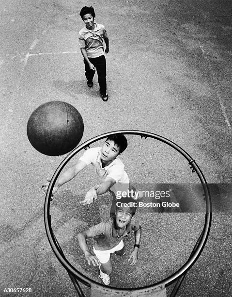 Tie Yang Huang Won Go and Gary Tam play basketball at a playground on Oak Street in Boston's Chinatown on July 26, 1987.
