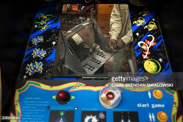 Charles Smellie is seen through the cabinet for a Galaga arcade game as he works on the game's picture tube at Video Amusements and Pinball Repairs...