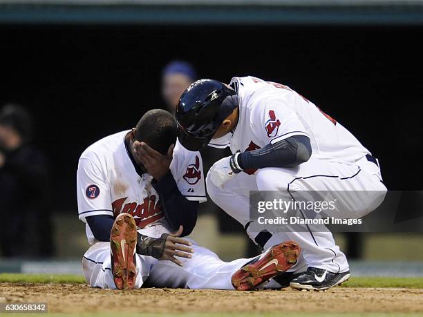 Leftfielder Michael Brantley of the Cleveland Indians assists centerfielder Michael Bourn at home plate after Bourn was injured sliding into home...