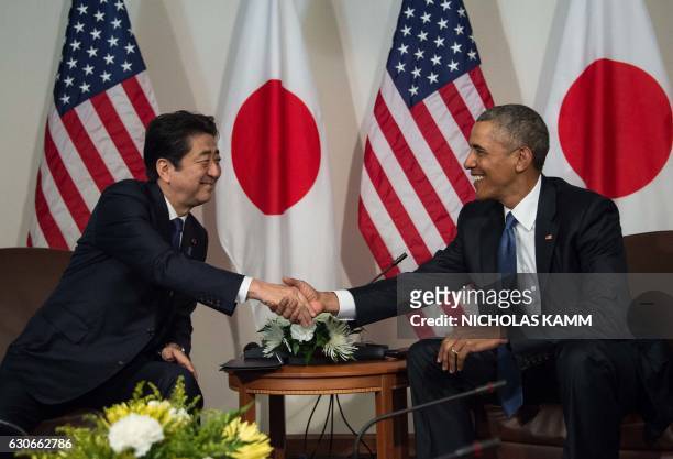 President Barack Obama shakes hands with Japanese Prime Minister Shinzo Abe December 27, 2016 during a meeting in Honolulu, Hawaii prior to visiting...