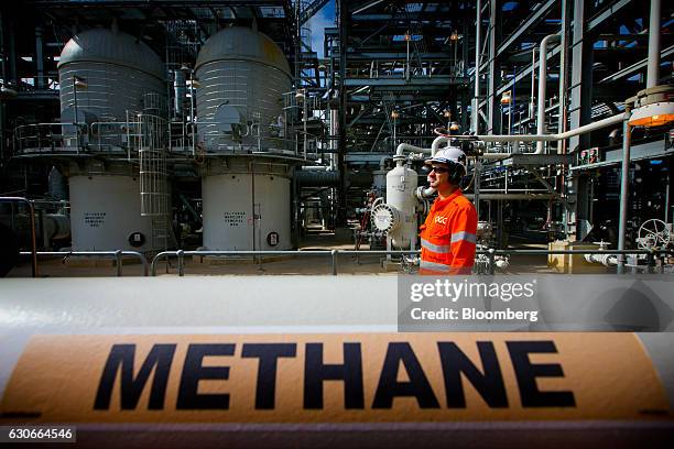 Worker walks past a gas pipe marked "Methane" at the Curtis Island liquefied natural gas plant, a part of the Queensland Curtis Liquefied Natural Gas...