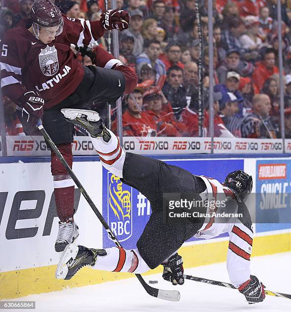 Blake Speers of Team Canada takes a big hit from Kristians Rubins of Team Latvia during a preliminary game in the 2017 IIHF World Junior Hockey...