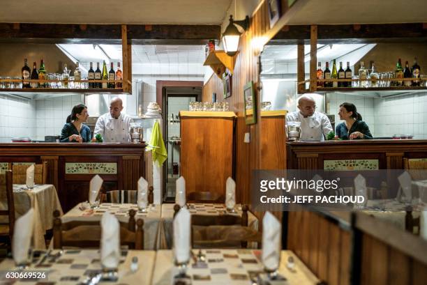 Cesar Asfar and his wife Rima, refugees from Syria and restaurant owners, are reflected in a mirror as they work in the kitchen of their restaurant...