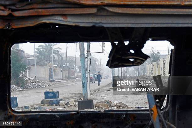 Picture taken through the window of a destroyed vehicle shows an Iraqi man walking down a destroyed street in the city of Fallujah, that was...
