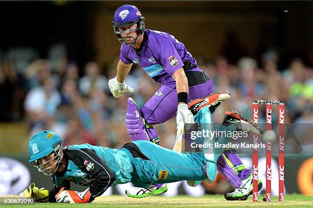 Dan Christian of the Hurricanes gets the ball past wicketkeeper Jimmy Peirson of the Heat during the Big Bash League between the Brisbane Heat and...