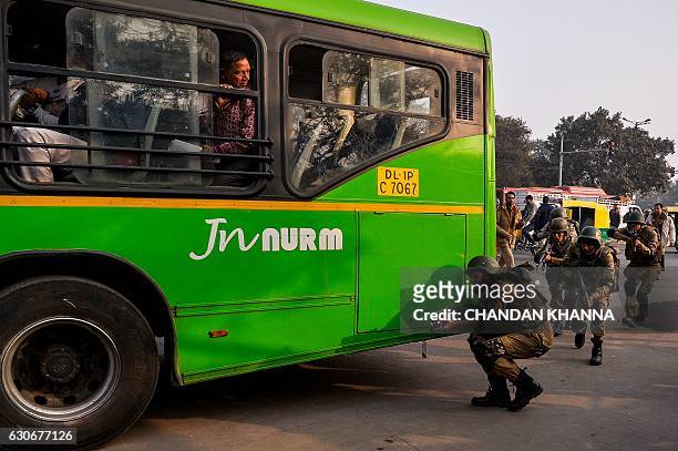 Indian SWAT commando personnel take part in a mock drill of bus hijack in New Delhi on December 30, 2016. / AFP / CHANDAN KHANNA