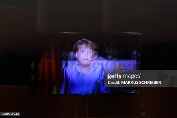 In this photo a television screen with German Chancellor Angela Merkel is reflected in a window during the recording of her annual New Year's speech...