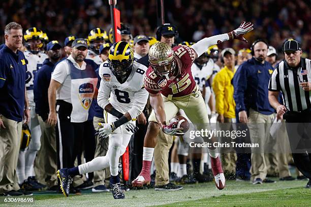 Travis Rudolph of the Florida State Seminoles tries to avoid the tackle of Channing Stribling of the Michigan Wolverines in the first half during the...
