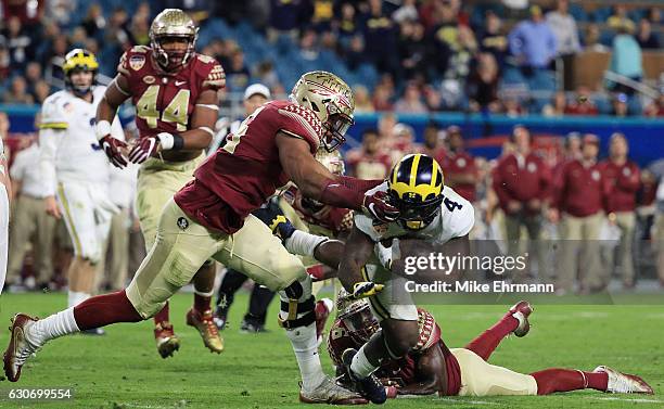 Jacob Pugh of the Florida State Seminoles grabs the face mask of De'Veon Smith of the Michigan Wolverines in the third quarter during the Capitol One...