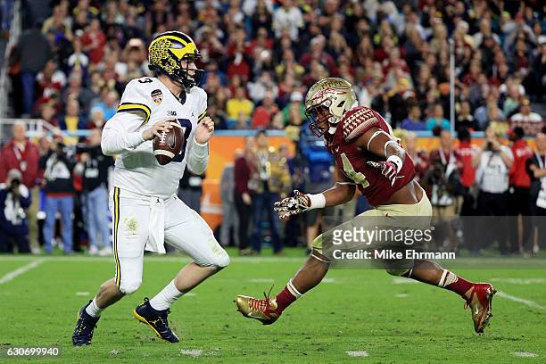 Wilton Speight of the Michigan Wolverines looks to pass as DeMarcus Walker of the Florida State Seminoles defends in the first half during the...