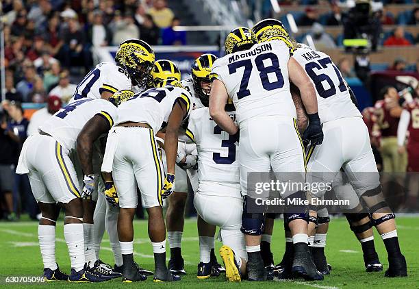 The Michigan Wolverines huddle in the first half against the Florida State Seminoles during the Capitol One Orange Bowl at Sun Life Stadium on...