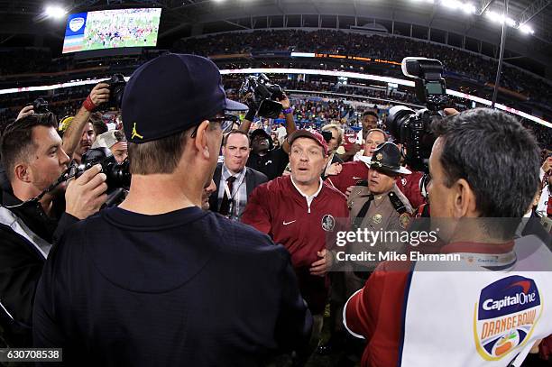 Head coach Jimbo Fisher of the Florida State Seminoles shakes hands with head coach Jim Harbaugh of the Michigan Wolverines after the Seminoles...