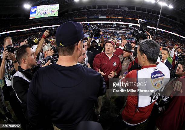 Head coach Jimbo Fisher of the Florida State Seminoles shakes hands with head coach Jim Harbaugh of the Michigan Wolverines after the Seminoles...