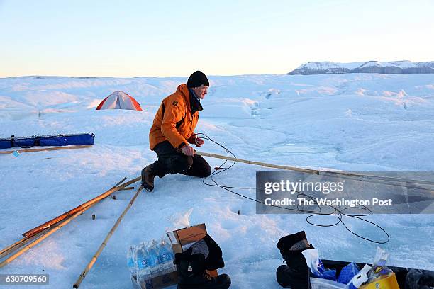 Keith Nicholls, a glaciologist from the British Antarctic Survey, works late in the evening on Petermann glacier on August 27, 2016. The scientists...