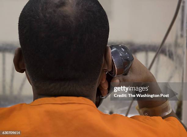 An inmate demonstrates the use of phones in the visitation area of the DC Central Detention Facility in Washington, DC on November 22, 2016. Young...