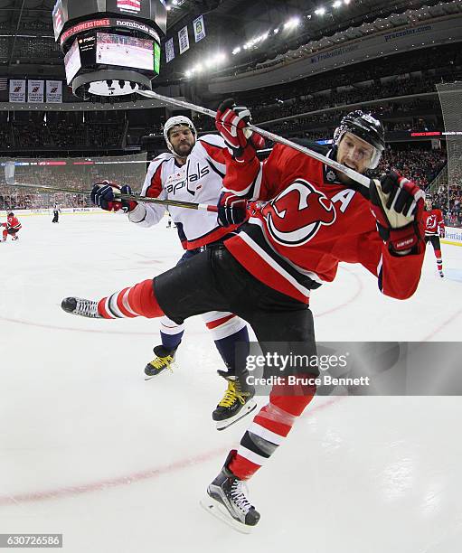 Alex Ovechkin of the Washington Capitals checks Travis Zajac of the New Jersey Devils during the first periodat the Prudential Center on December 31,...