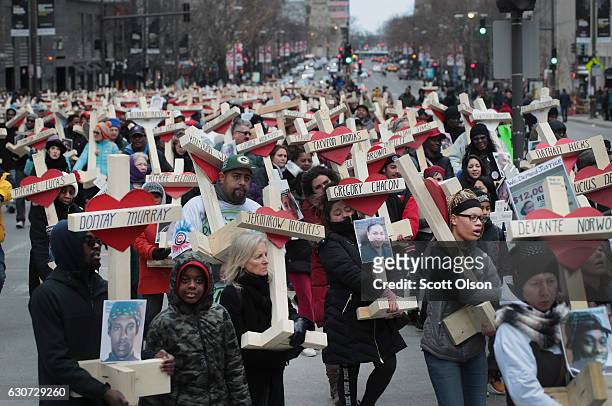 Residents, activists, and friends and family members of victims of gun violence march down Michigan Avenue carrying nearly 800 wooden crosses bearing...