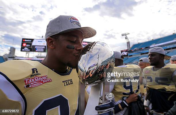 Marcus Allen of the Georgia Tech Yellow Jackets kisses the TaxSlayer Bowl trophy after the game against the Kentucky Wildcats at EverBank Field on...