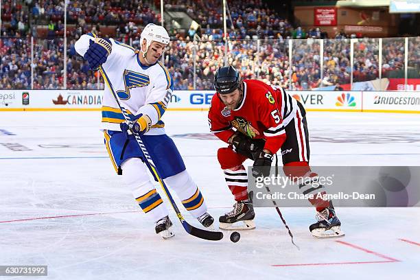 Barrett Jackman of the St. Louis Blues Alumni Team and Ben Eager of the Chicago Blackhawks Alumni Team chase the puck during the Alumni Game as part...