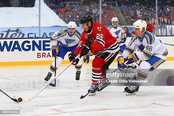 Grant Mulvey of the Chicago Blackhawks handles the puck against Pierre Turgeon and Scott Young of the St. Louis Blues the St. Louis Blues during the...