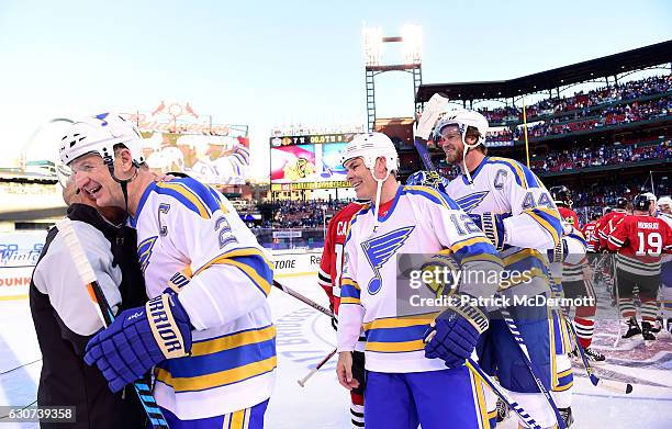 Al MacInnis of the St. Louis Blues gets a hug from sportscaster and Chicago Blackhawks alumni Darren Pang as Adam Oates and Chris Pronger of the St....