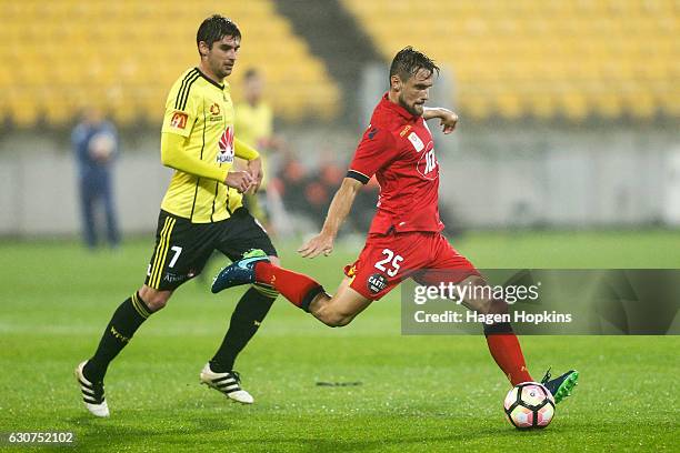 James Holland of Adelaide United passes while Gui Finkler of the Phoenix looks on during the round 13 A-League match between Wellington Phoenix and...