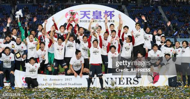 Kashima Antlers captain and midfielder Mitsuo Ogasawara raises the Emperor's Cup trophy with his team officials and players after their victory over...