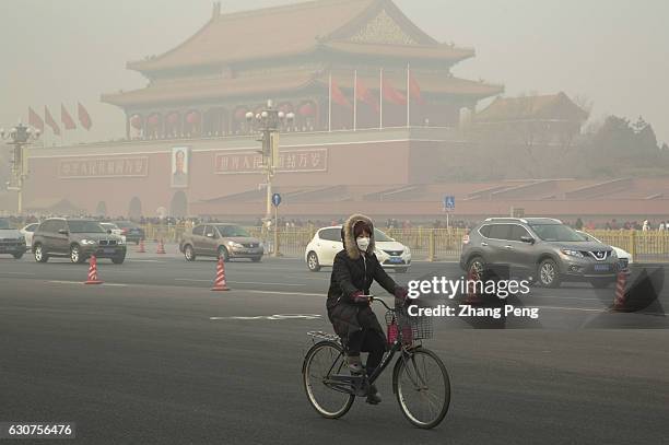 Woman, wearing a mask, rides a bike past Tiananmen Rostrum. On the first day of 2017, Beijing suffered its first severe haze disaster of the new...