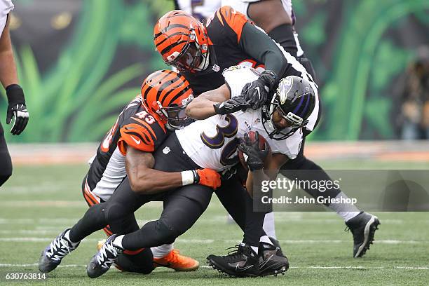 Kenneth Dixon of the Baltimore Ravens is tackled by Carlos Dunlap of the Cincinnati Bengals and George Iloka of the Cincinnati Bengals during the...